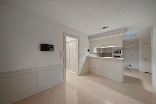 kitchen with kitchen peninsula, stainless steel microwave, and a textured ceiling