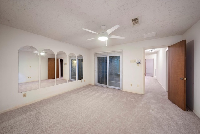 unfurnished room with ceiling fan, light colored carpet, and a textured ceiling