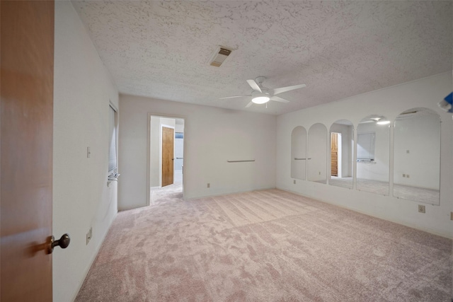 spare room featuring ceiling fan, light colored carpet, and a textured ceiling