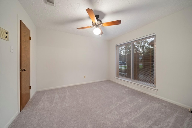 carpeted spare room featuring a textured ceiling and ceiling fan