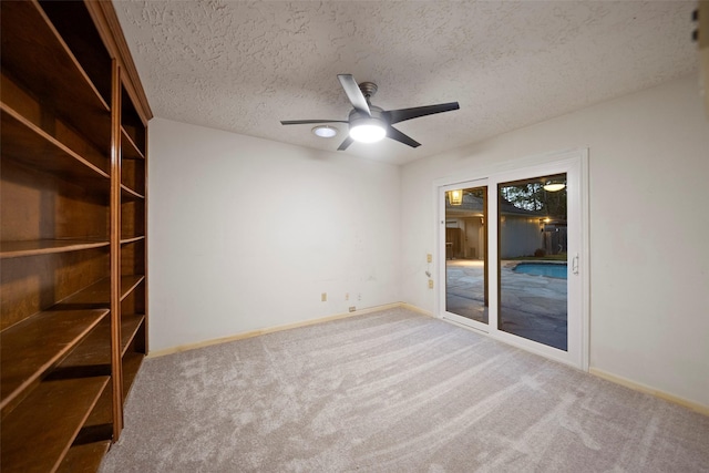 carpeted spare room with a textured ceiling and ceiling fan