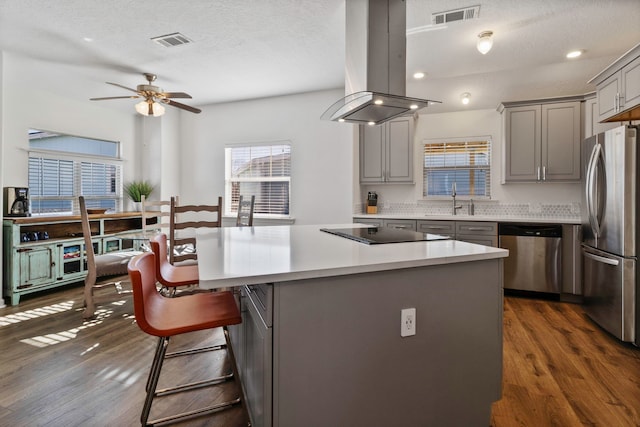 kitchen with island range hood, dark hardwood / wood-style floors, a center island, decorative backsplash, and appliances with stainless steel finishes