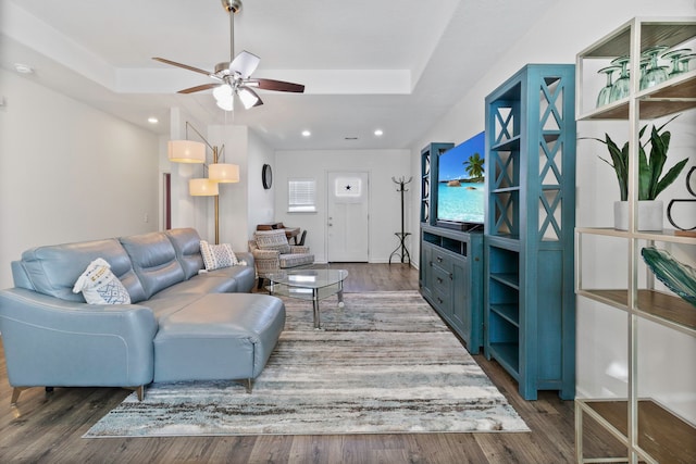 living room with ceiling fan, a tray ceiling, and hardwood / wood-style floors