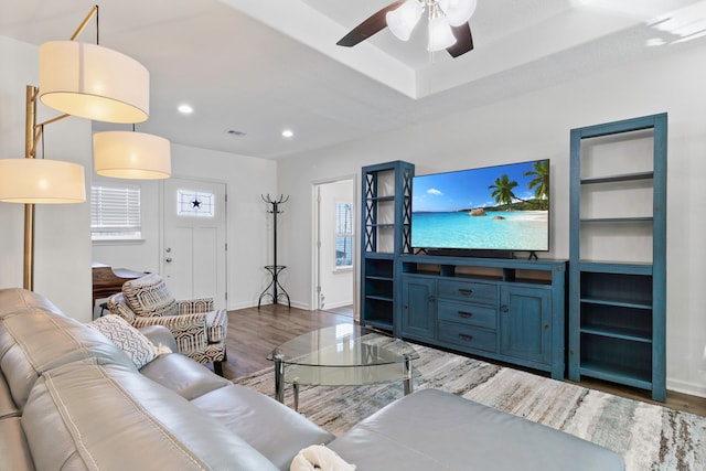 living room featuring ceiling fan, built in features, a raised ceiling, and dark hardwood / wood-style floors