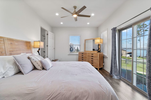 bedroom featuring dark hardwood / wood-style flooring, ceiling fan, and a water view