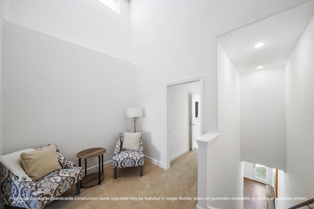 sitting room featuring light carpet and a towering ceiling