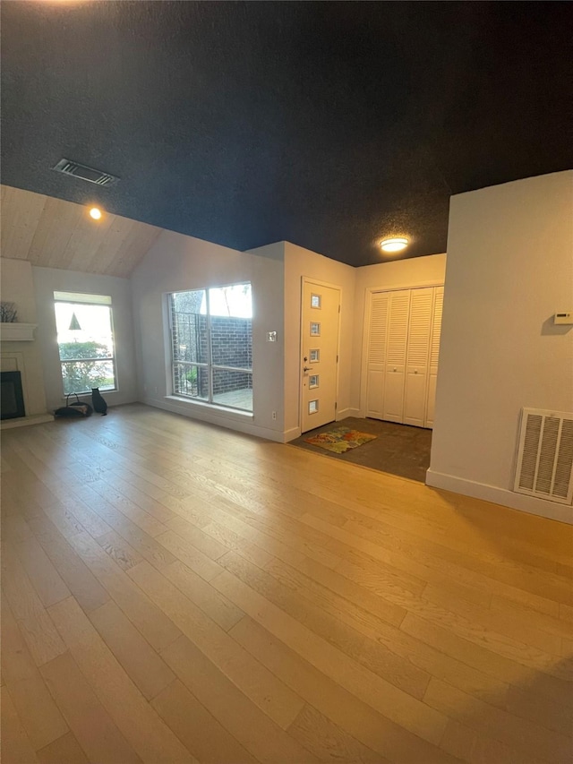 unfurnished living room with lofted ceiling and light wood-type flooring