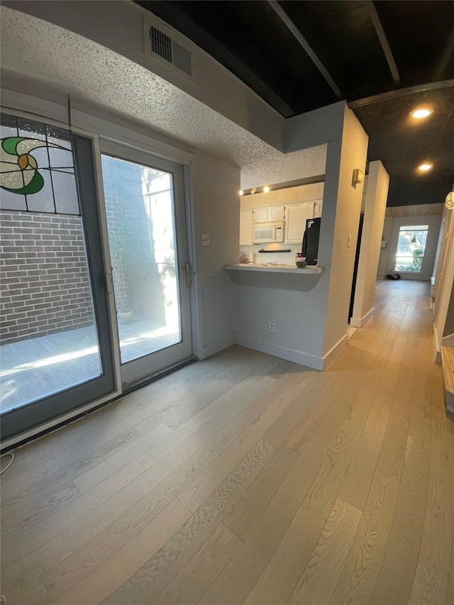 unfurnished living room featuring a textured ceiling and light hardwood / wood-style floors