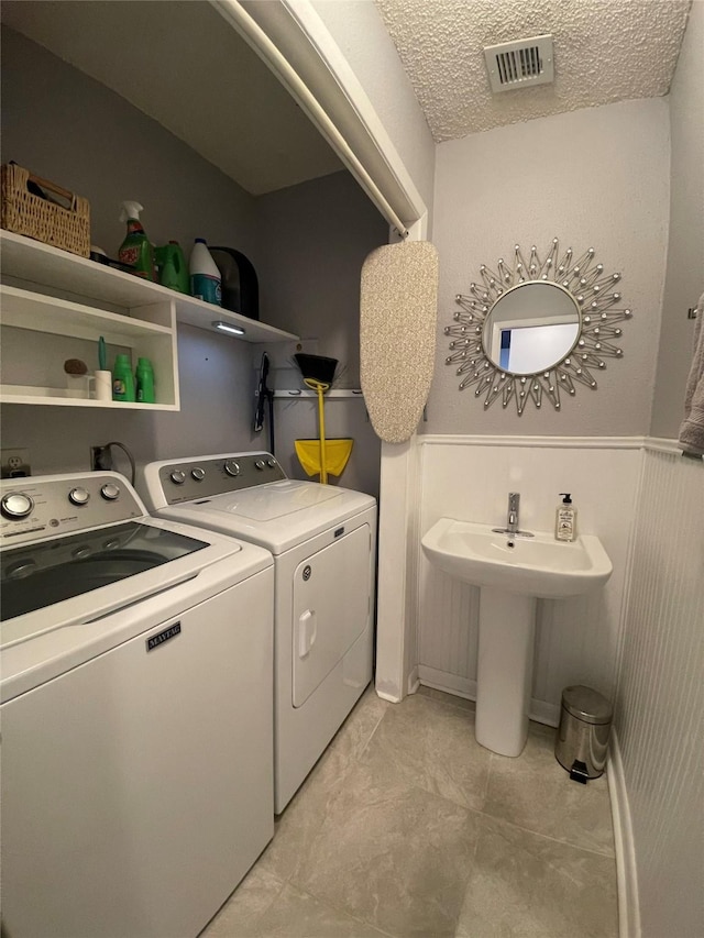 washroom featuring washer and clothes dryer, a textured ceiling, and sink