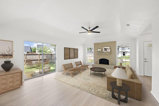 living room featuring ceiling fan, a large fireplace, and light hardwood / wood-style flooring