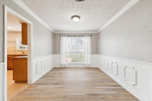 unfurnished room with ornamental molding, sink, and light hardwood / wood-style floors