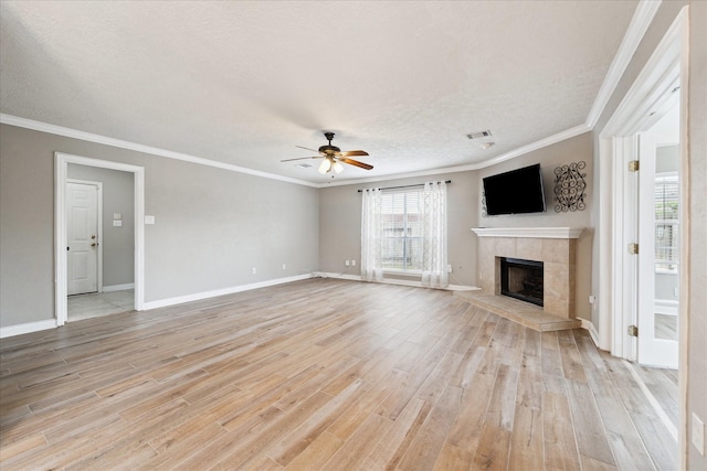 unfurnished living room featuring a textured ceiling, light hardwood / wood-style flooring, ornamental molding, a tile fireplace, and ceiling fan