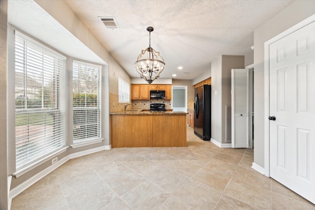 kitchen featuring sink, an inviting chandelier, tasteful backsplash, black appliances, and kitchen peninsula