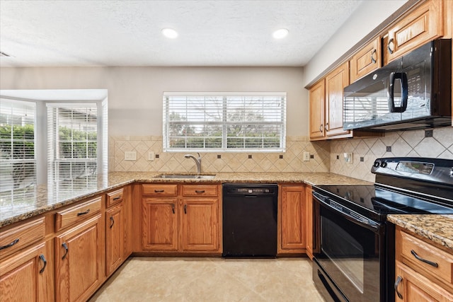 kitchen featuring light stone counters, sink, decorative backsplash, and black appliances