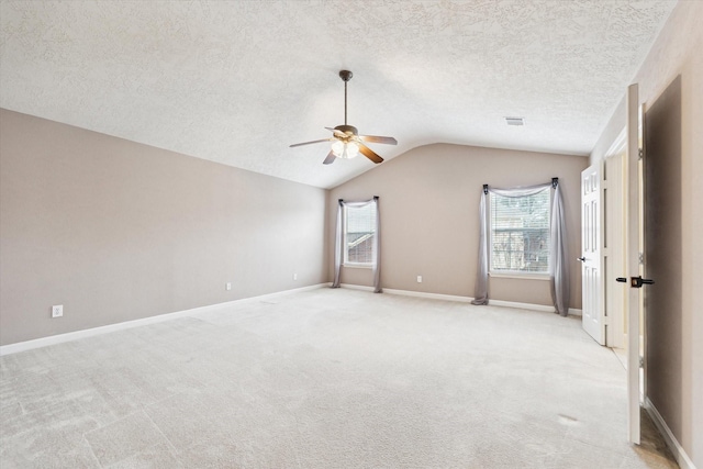 empty room with lofted ceiling, light carpet, a textured ceiling, and ceiling fan