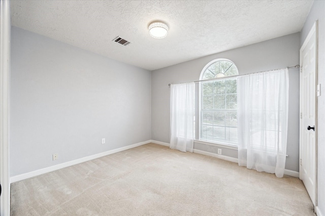 carpeted empty room featuring a textured ceiling