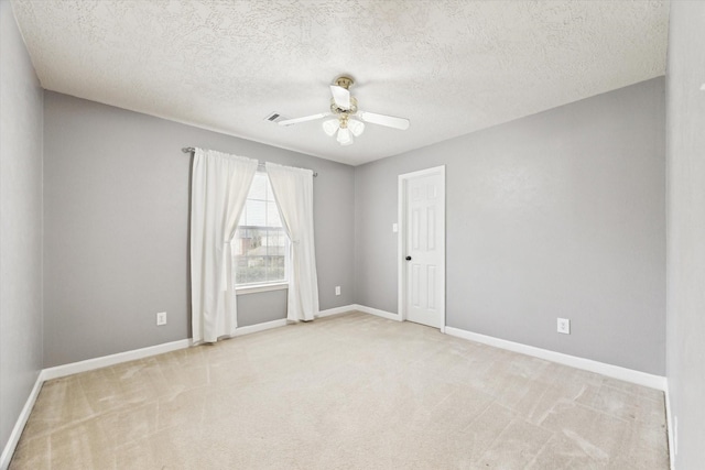 spare room featuring ceiling fan, light colored carpet, and a textured ceiling