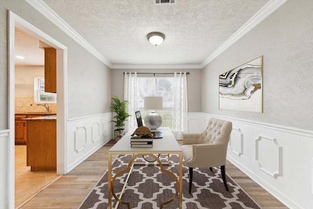 office with sink, crown molding, a textured ceiling, and light wood-type flooring