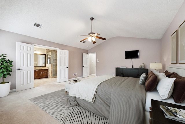 bedroom with light carpet, connected bathroom, vaulted ceiling, and ceiling fan