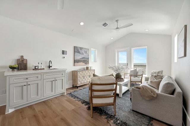 living area featuring ceiling fan, sink, lofted ceiling, and light wood-type flooring