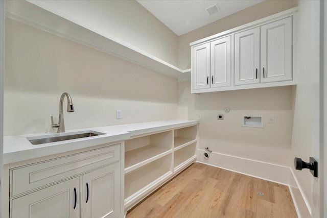 washroom featuring cabinets, gas dryer hookup, sink, hookup for a washing machine, and light wood-type flooring