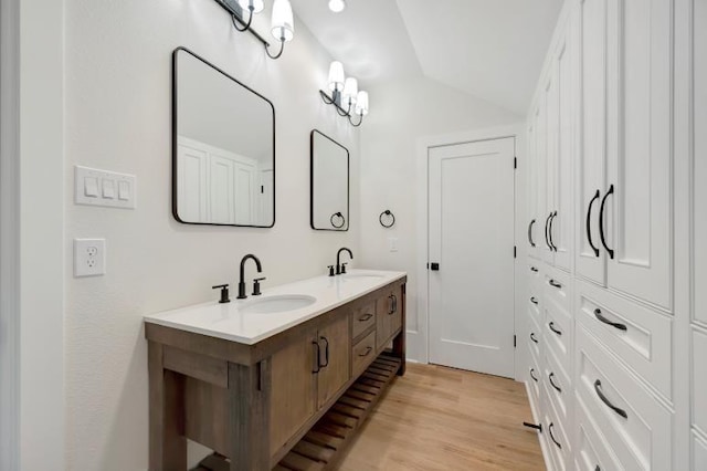 bathroom featuring hardwood / wood-style floors, vanity, and vaulted ceiling