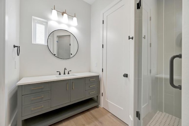 bathroom with vanity, hardwood / wood-style flooring, and a shower with door