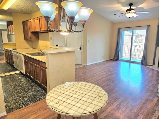 kitchen featuring ceiling fan with notable chandelier, sink, a textured ceiling, dark hardwood / wood-style flooring, and kitchen peninsula