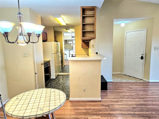 kitchen with an inviting chandelier, white refrigerator, separate washer and dryer, a textured ceiling, and kitchen peninsula