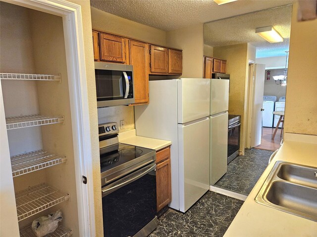 kitchen with sink, washer and dryer, a textured ceiling, and appliances with stainless steel finishes