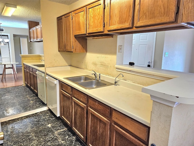 kitchen featuring stainless steel dishwasher, sink, and a textured ceiling