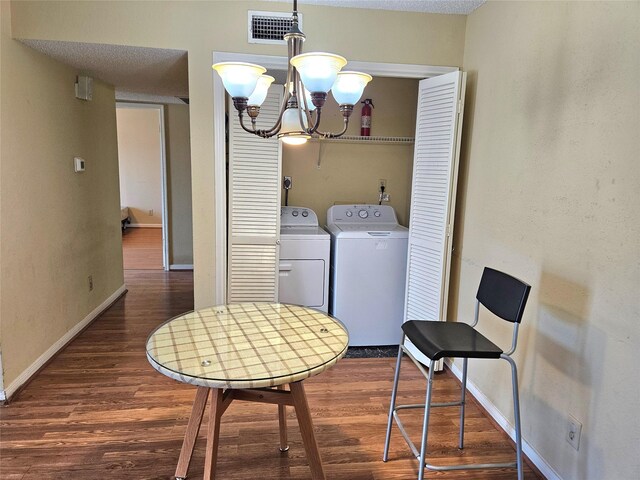 clothes washing area with separate washer and dryer, dark wood-type flooring, a chandelier, and a textured ceiling