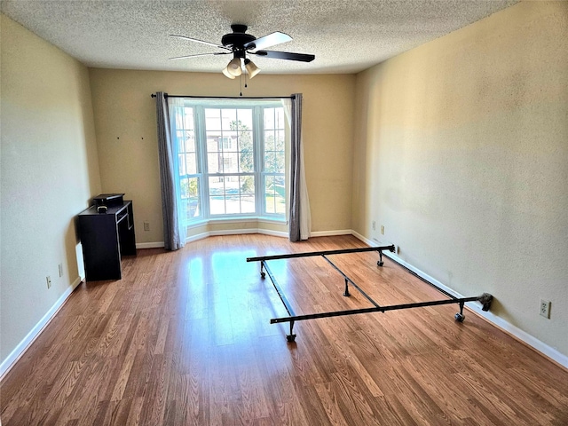 workout room featuring ceiling fan, a textured ceiling, and hardwood / wood-style flooring