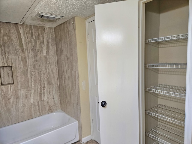 bathroom featuring a textured ceiling and bathing tub / shower combination