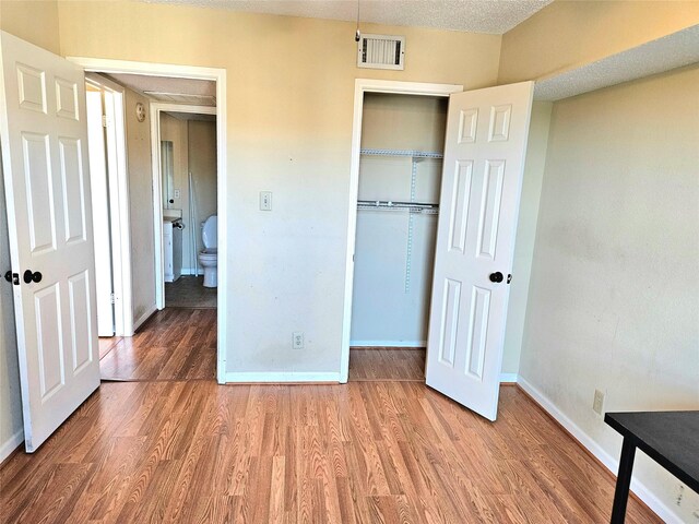 unfurnished bedroom featuring a closet, hardwood / wood-style floors, and a textured ceiling