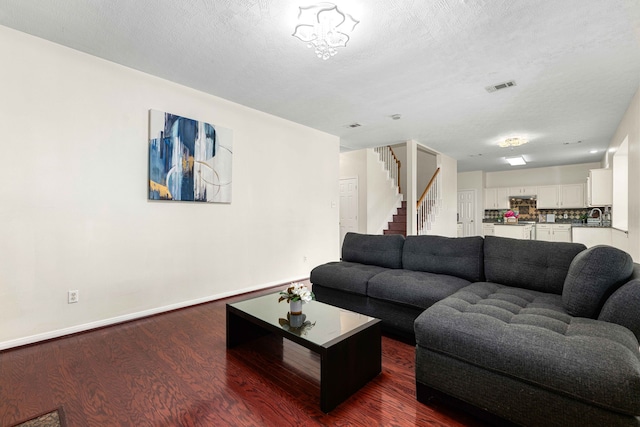 living room featuring sink, a textured ceiling, and dark hardwood / wood-style floors