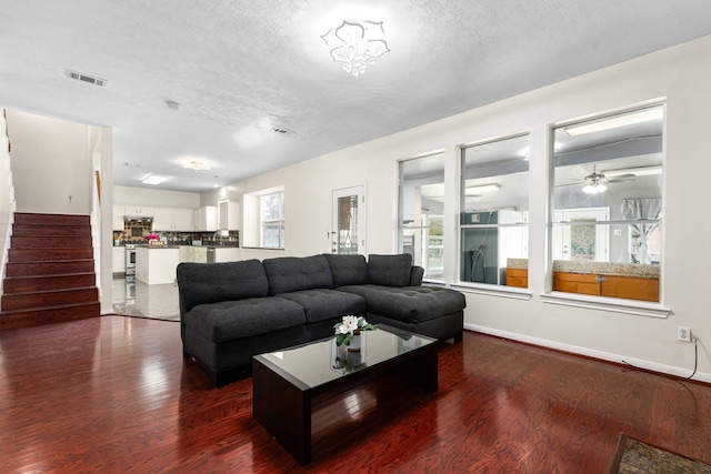 living room with dark hardwood / wood-style flooring, a textured ceiling, and ceiling fan