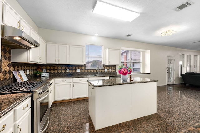 kitchen featuring stainless steel range, dark stone counters, a kitchen island, white cabinets, and sink