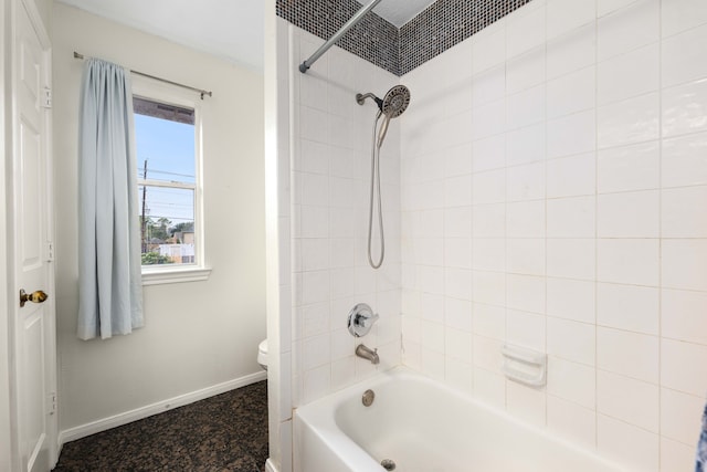 bathroom featuring tiled shower / bath combo and toilet