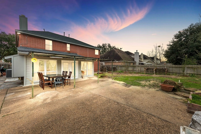 back house at dusk featuring central air condition unit and a patio area