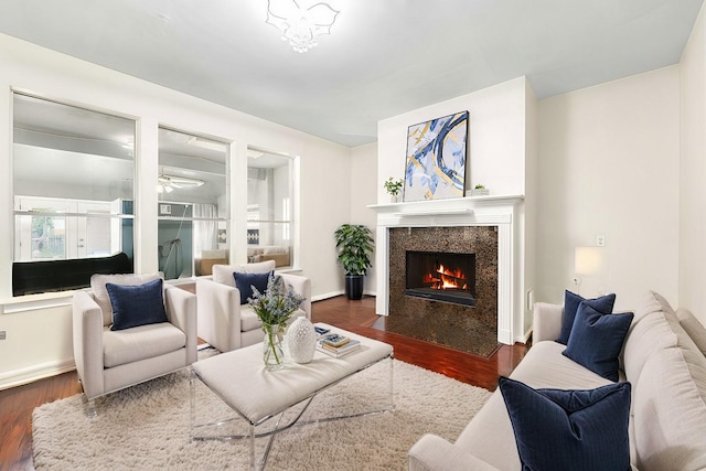 living room with a high end fireplace, ceiling fan, and dark hardwood / wood-style floors