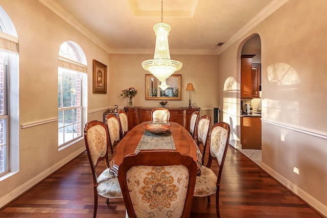 dining room with ornamental molding, dark hardwood / wood-style floors, an inviting chandelier, and a tray ceiling