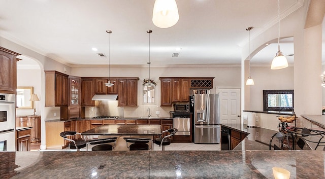 kitchen featuring appliances with stainless steel finishes, hanging light fixtures, ornamental molding, and sink