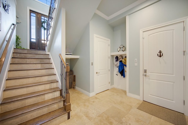 entrance foyer with light tile patterned floors, baseboards, and stairs
