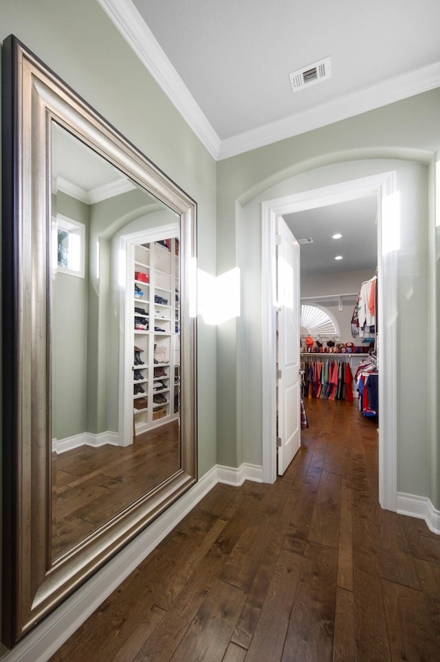 hallway featuring crown molding, visible vents, dark wood-style flooring, and baseboards