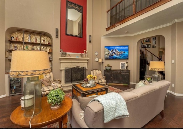 living room with dark hardwood / wood-style floors, crown molding, beverage cooler, and a high ceiling