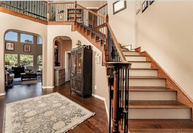 stairway featuring a towering ceiling and hardwood / wood-style flooring