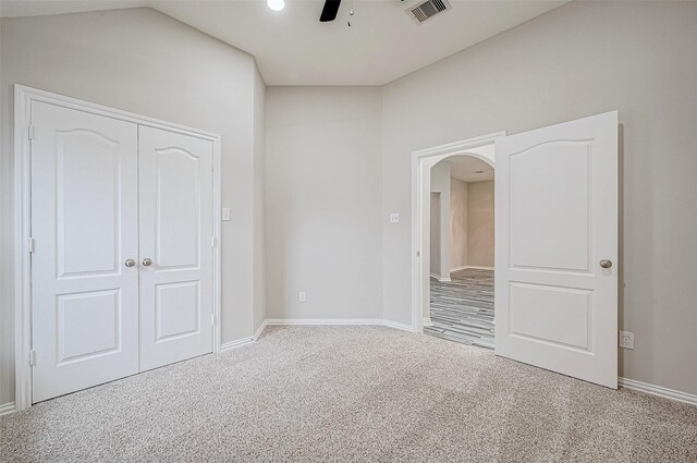 unfurnished bedroom with carpet flooring, a closet, ceiling fan, and vaulted ceiling