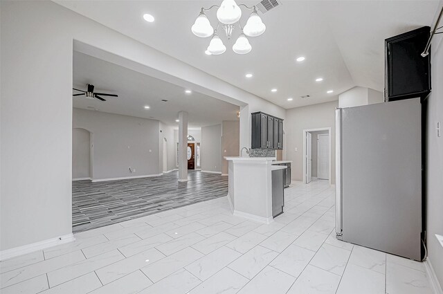 kitchen with decorative backsplash, ceiling fan with notable chandelier, and stainless steel refrigerator