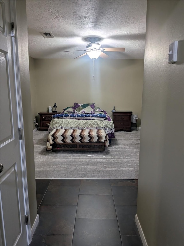 tiled bedroom with a textured ceiling and ceiling fan